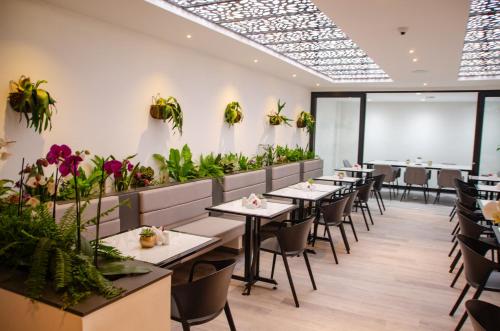 波哥大Hotel ByHours Las Américas的一间设有桌椅的餐厅,种植了植物