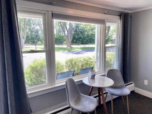Elk RapidsElk Rapids Lakeshore Inn的客房设有桌椅和窗户。