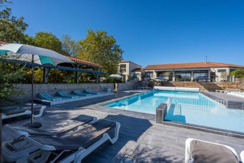 滨海昂古兰Côté Océan Resort的一个带躺椅和遮阳伞的游泳池