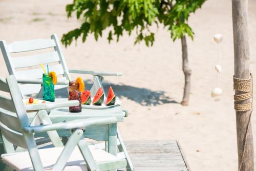 斯卡拉伯塔麦斯PELAGO BUNGALOWS的海滩上的白色椅子,配有一张桌子和饮料