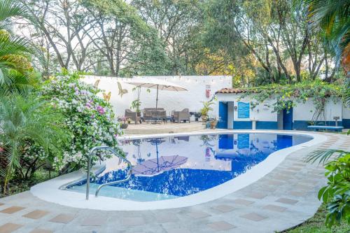阿拉胡埃拉Hotel Aeropuerto的一座带房子的庭院内的游泳池