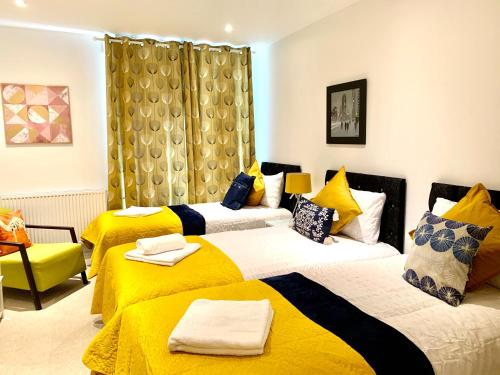 伦敦Dockland Excel 2 Bedroom Apartment的酒店客房带两张带黄床单的床
