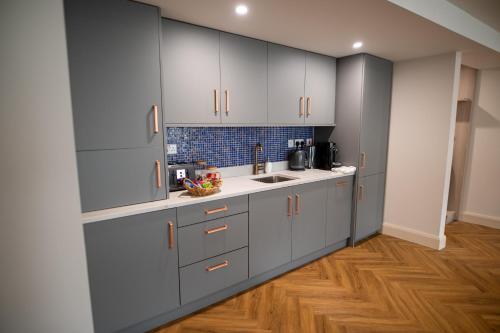 基尔肯尼Kilkenny Suites的厨房铺有木地板,配有灰色橱柜。