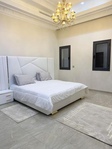 RejicheVilla Artemis (Ground Floor)的一间带白色床的卧室,位于一个吊灯的房间