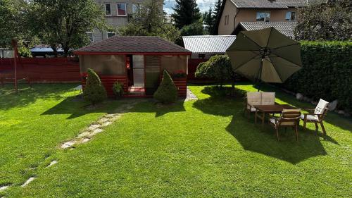 考纳斯Japandi apartamentai的后院,草地上摆放着桌子和雨伞