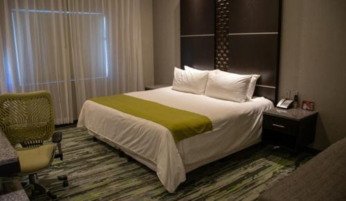 圣路易斯里奥科罗拉多Hotel Araiza San Luis R.C.的配有一张床和一把椅子的酒店客房