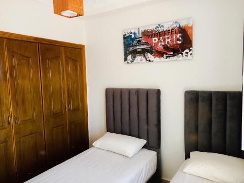 丹吉尔Fantastique Appartement avec piscine sur la plage M2的卧室配有两张床,墙上挂有一张海报