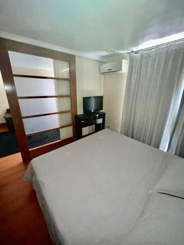 圣地亚哥Departamento en las condes, ubicacion perfecta.的卧室配有白色的床和电视。