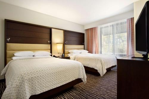 费耶特维尔Embassy Suites by Hilton Fayetteville Fort Bragg的酒店客房设有两张床和一台平面电视。