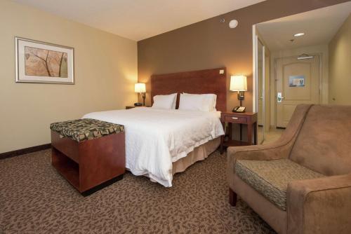 Yazoo City亚祖城汉普顿酒店的配有一张床和一把椅子的酒店客房