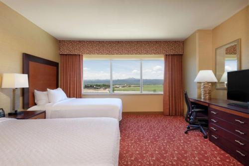 拉夫兰Embassy Suites by Hilton Loveland Conference Center的酒店客房设有两张床、一张书桌和一个窗户。