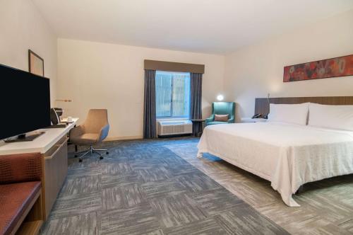 克林顿Hilton Garden Inn Jackson/Clinton的配有一张床和一台平面电视的酒店客房