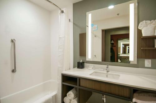 克林顿Hilton Garden Inn Jackson/Clinton的一间带水槽、浴缸和镜子的浴室