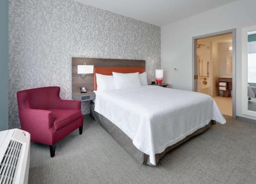 黑格斯敦Home2 Suites By Hilton Hagerstown的一间卧室配有一张大床和一张红色椅子