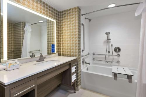 威尔明顿Home2 Suites Wilmington的一间带水槽、浴缸和镜子的浴室