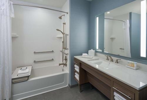帕诺滩Home2 Suites By Hilton Pompano Beach Pier, Fl的一间带水槽、浴缸和镜子的浴室