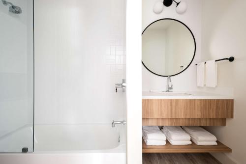 乔治敦Hampton by Hilton Grand Cayman Seven Mile Beach的带淋浴、盥洗盆和镜子的浴室