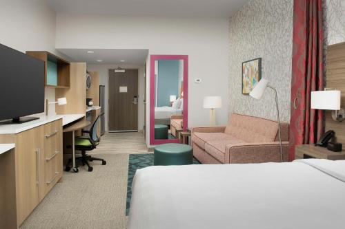 迈尔斯堡Home2 Suites by Hilton Fort Myers Airport的配有一张床和一张书桌的酒店客房
