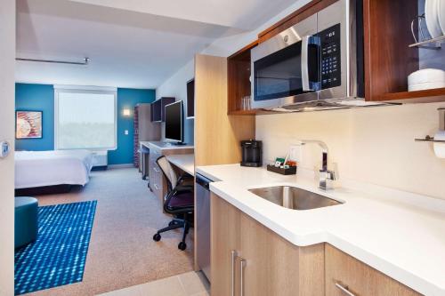 Byron CenterHome2 Suites By Hilton Grand Rapids South的一个带水槽的厨房和一张位于客房内的床