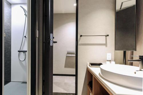 名古屋Best Western Plus Nagoya Sakae的一间带水槽和玻璃淋浴间的浴室
