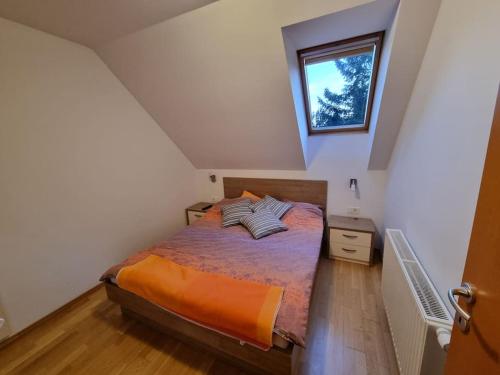 兹雷切Macesen apartment Rogla的一间卧室配有一张带橙色毯子和窗户的床。