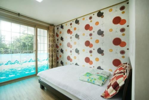 西归浦市Sanbangsan Hot Spring Pension的一间卧室设有一张床和鲜花墙