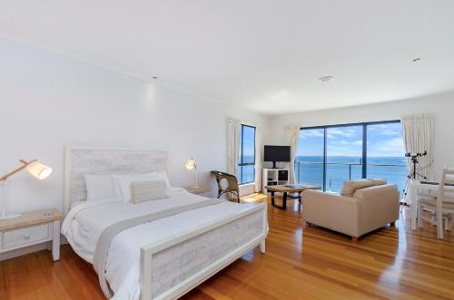 波特兰Clifftop Apartments Portland Vic的卧室配有一张白色大床和一把椅子