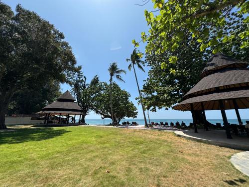 高兰Beach Bungalow at Lanta Resort的一片带遮阳伞的海滩,人们坐在草地上