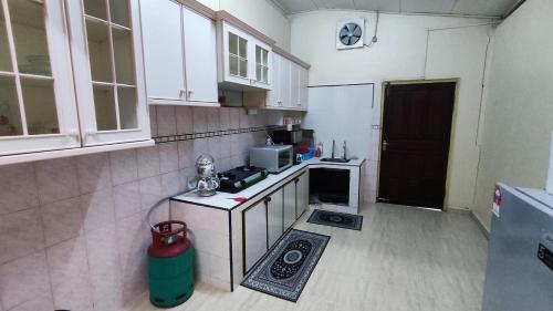 巴西富地Nik Legacy Homestay的小厨房配有白色橱柜和炉灶。