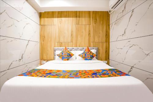 孟买FabHotel Shubham Inn的卧室配有一张带彩色枕头的大型白色床。