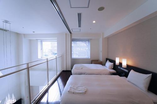 仙台KOKO HOTEL Sendai Kotodai Park的酒店客房设有两张床和一个阳台。