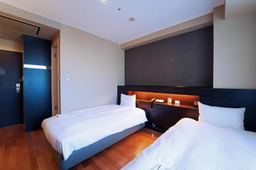 仙台KOKO HOTEL Sendai Kotodai Park的两张位于酒店客房的床,配有两张sidx sidx单人床