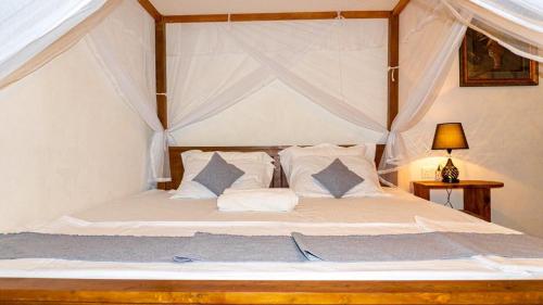 阿杭格默Ostello Surf Resort的卧室配有带白色床单和枕头的天蓬床。
