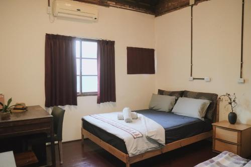 高雄眷村恋影民宿的一间卧室配有一张床、一张书桌和一个窗户。