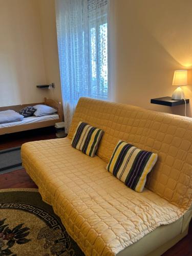 Svetozar MiletićGuest House Anna Vendégház的客房内的一张黄色沙发,配有两个枕头