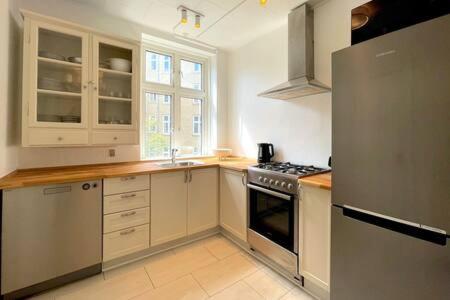 哥本哈根2 Bedroom Flat in Trendy Area的厨房配有白色橱柜和不锈钢冰箱