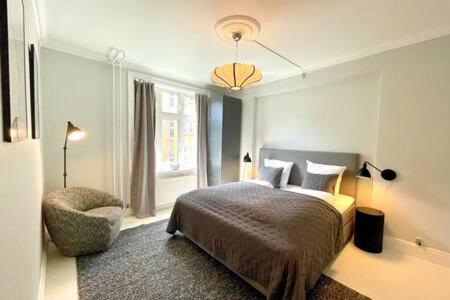 哥本哈根Flat in Trendy and Vibrant Nørrebro Area的卧室配有床、椅子和窗户。