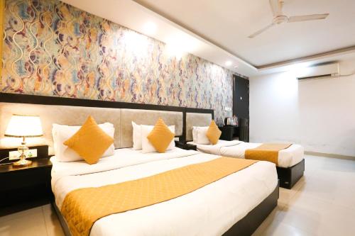新德里Hotel Aashiyana New Delhi的酒店客房设有两张床,墙上挂有绘画作品