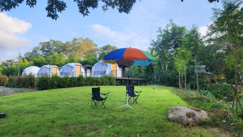 Pong TalongRiver hill khaoyai camping的院子里的一张桌子和两把椅子放在伞下