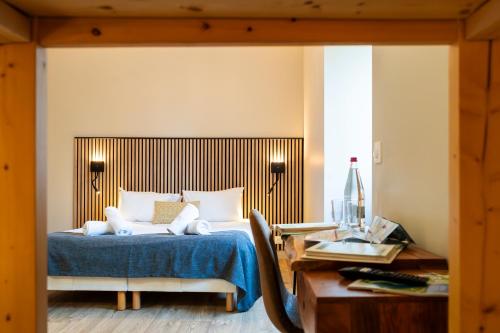 莱鲁斯Hôtel-Club Côté Dole, USSIM Vacances Les Rousses的一间卧室配有一张带蓝毯的床和一张书桌