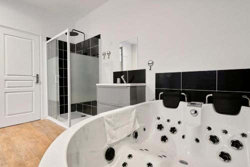 图尔昆NG SuiteHome - Lille I Tourcoing I Haute - Balnéo - Netflix的浴室铺有黑色瓷砖,配有大型白色浴缸。