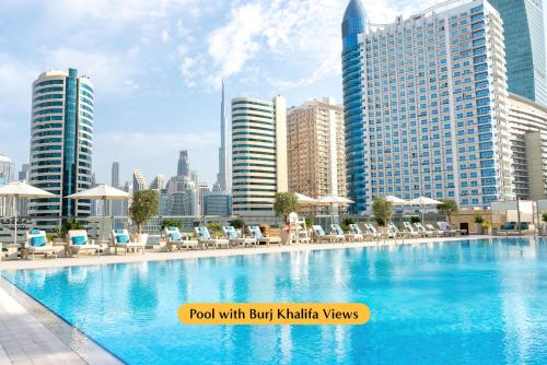 迪拜The First Collection Business Bay的城市里一个带椅子和遮阳伞的游泳池
