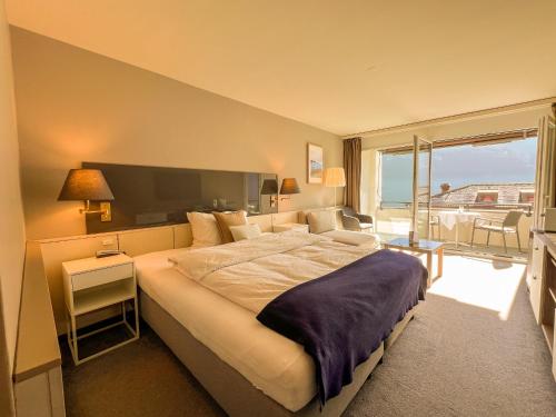 盖尔绍Seehotel Riviera at Lake Lucerne的一间带大床的卧室和一个阳台