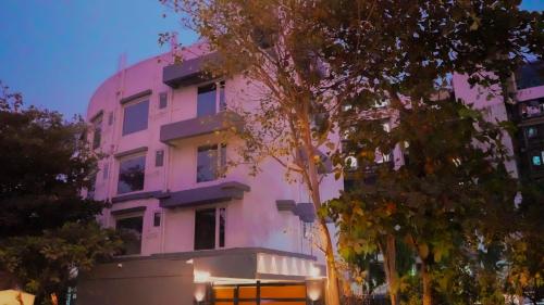 孟买Hsquare Hotel Andheri West的前面有树木的粉红色建筑