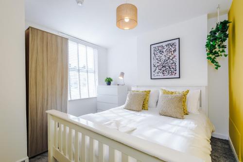 切斯特Large 7 bedroom town house in Chester City Centre的白色卧室配有一张带黄色枕头的大床