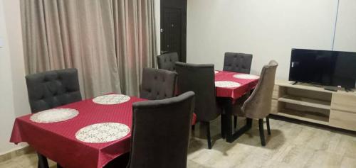 JiruBenji Apartments的一间带红色桌椅和电视的用餐室