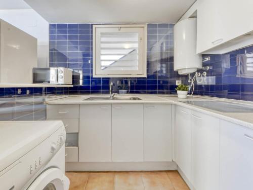 罗萨斯Apartment Platja de Roses-4 by Interhome的厨房配有白色橱柜和蓝色瓷砖