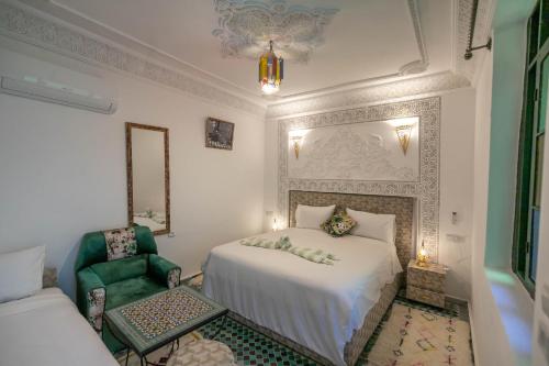 非斯Riad dar Yamna的卧室配有白色的床和绿色椅子