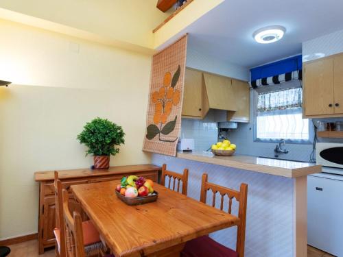 莱斯卡拉Apartment Residencial Gran Sol by Interhome的厨房配有木桌,上面放着一碗水果