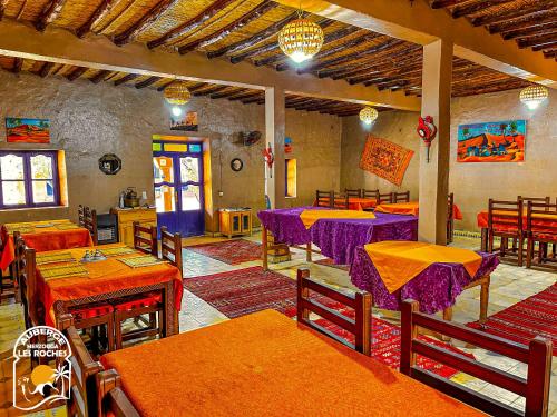 梅尔祖卡Riad Les Roches Merzouga的餐厅配有桌椅和紫色桌子